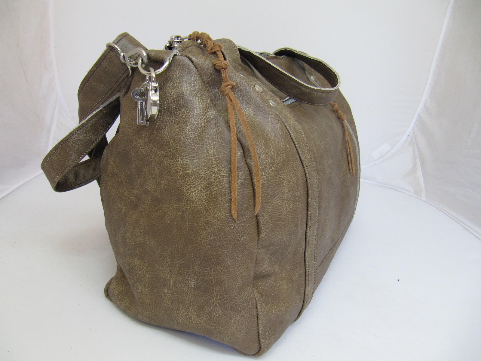 Overnight bag in light vintage leather and silver clips and zips.
