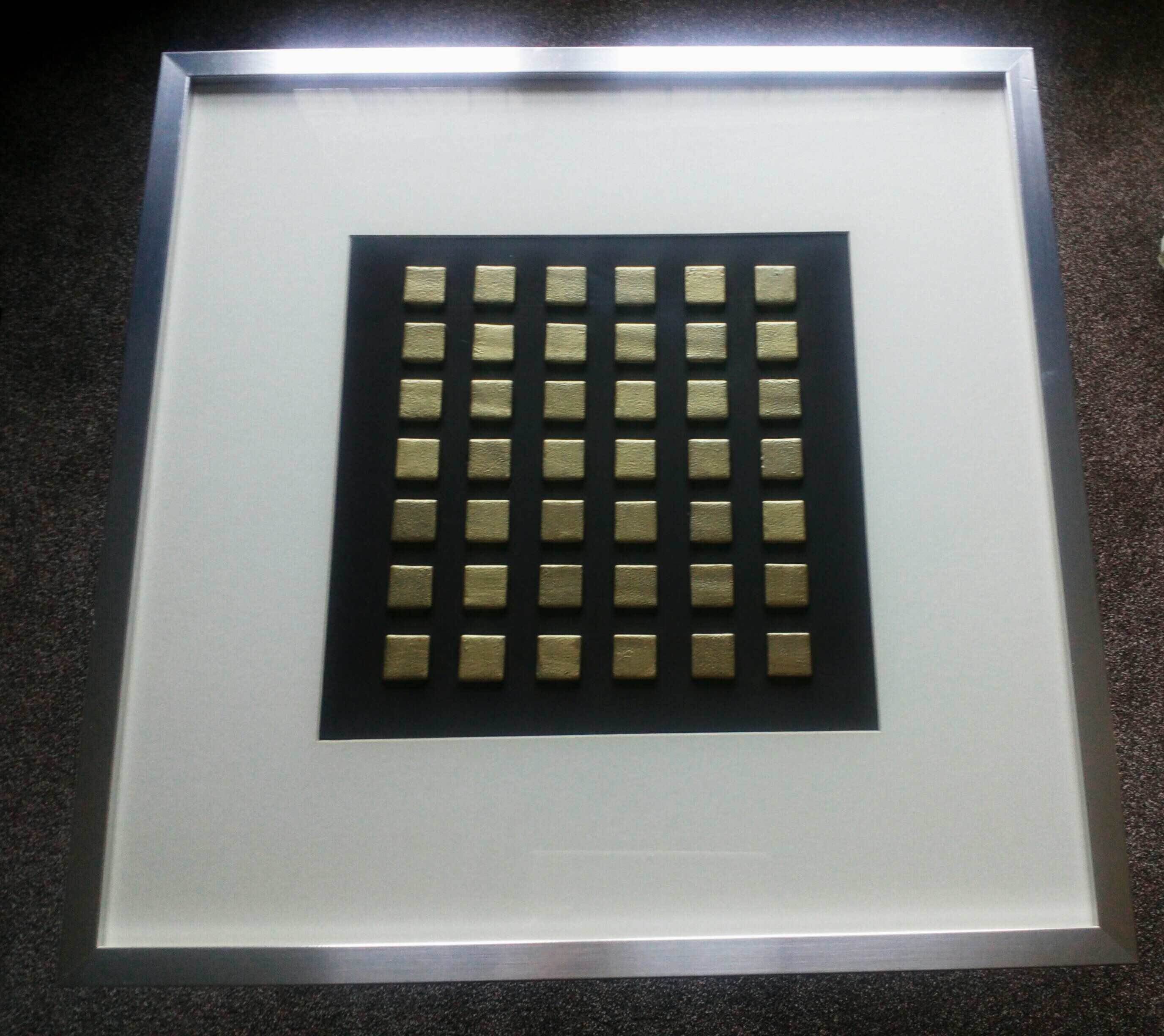 Gold glass tiles mounted on board. Brushed aluminium frame.