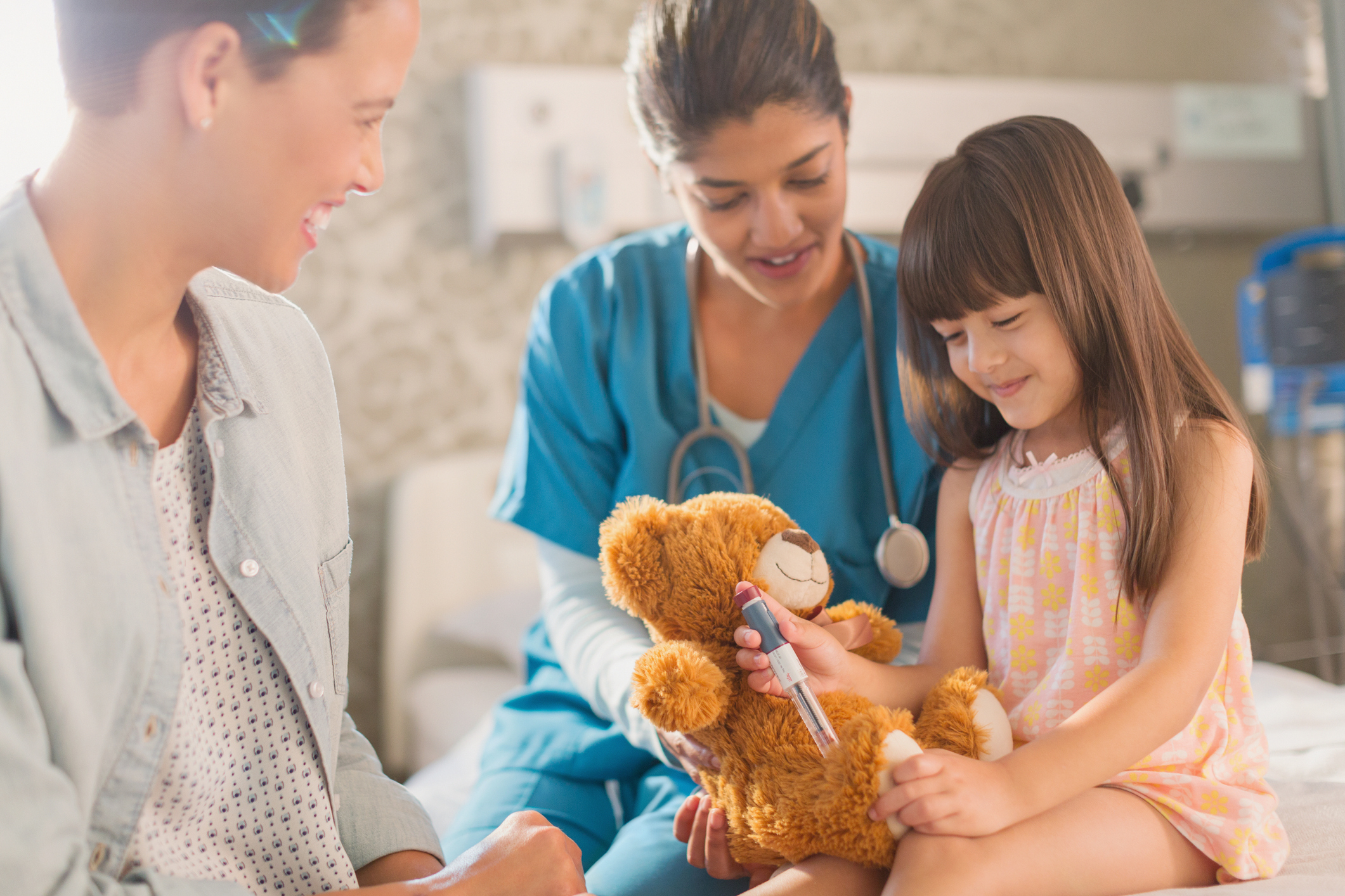 female-nurse-and-mother-watching-girl-patient-using-insulin-pen-on-teddy-bearjpg