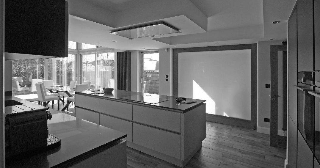 Internal photograph showing the kitchen area opening through to the dining area and through full height glazing to the sunny rear garden.