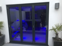 Three segment Aluminium Bifolding doors  into rendered walls, blue backlight
