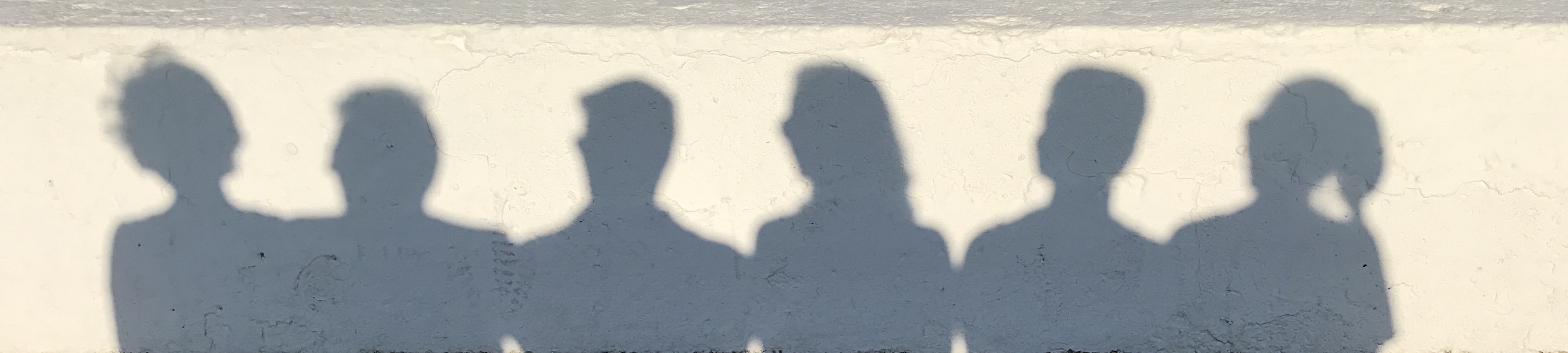 A shadow cast by the family all sitting on a wall on the seafront in Wimereux, France