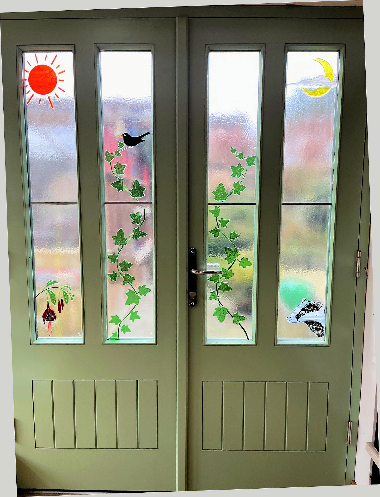 Set of fused-glass door-panels, featuring sun & moon, fuchsia flowers, ivy, badger & blackbird