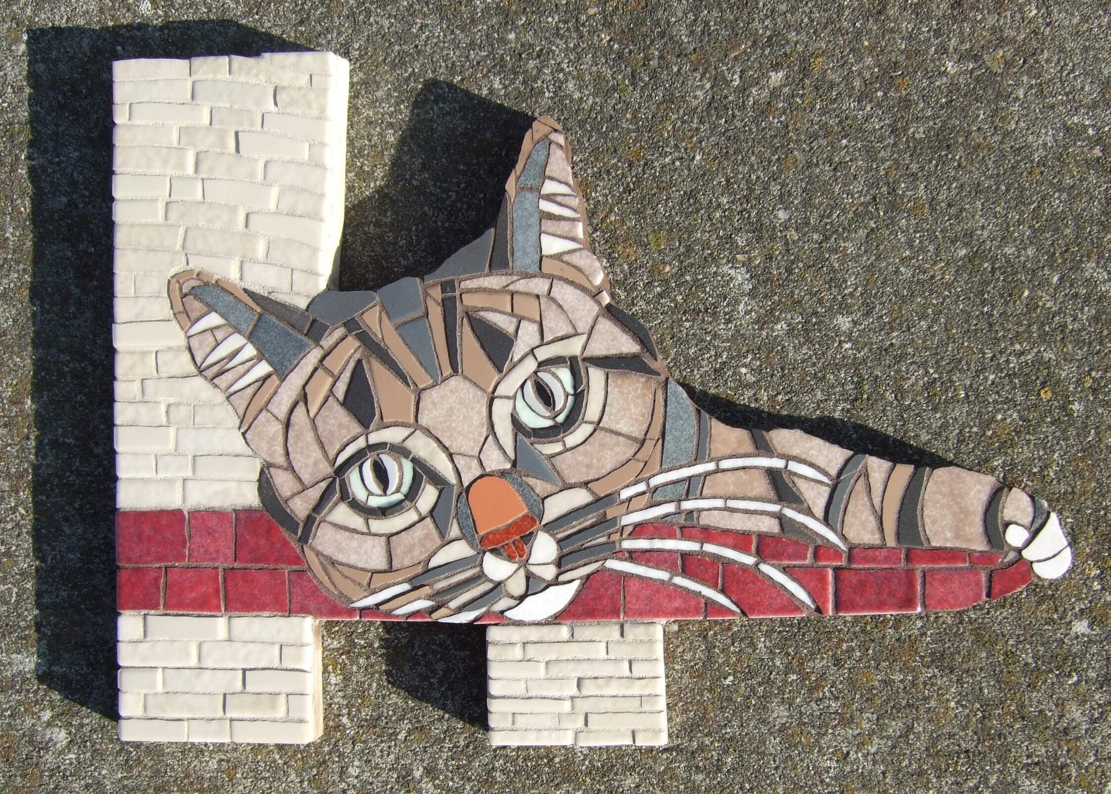 Een mozaiek van een kat die op een krabpaal ligt.
