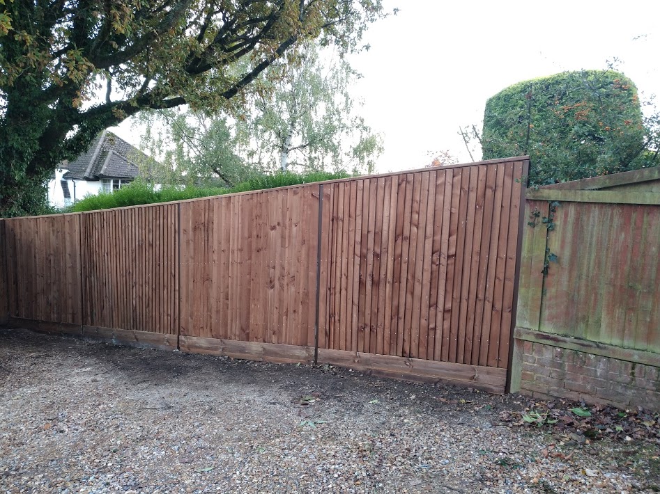 Capped 2M high dark brown timber fence on steel posts