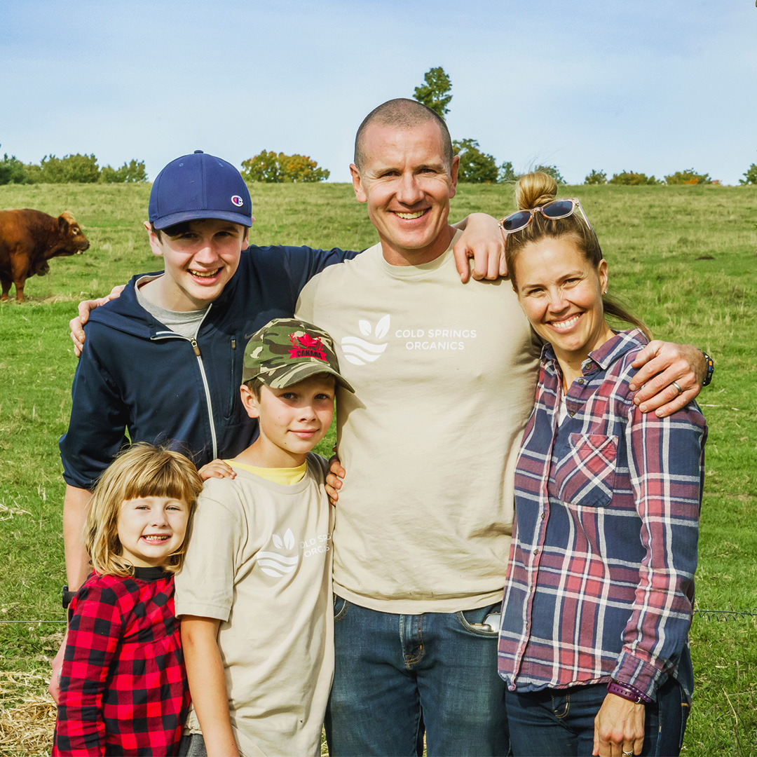 Farmer Glen Young and his family proudly smiling in front of their family owned organic farm in Northumberland Hills