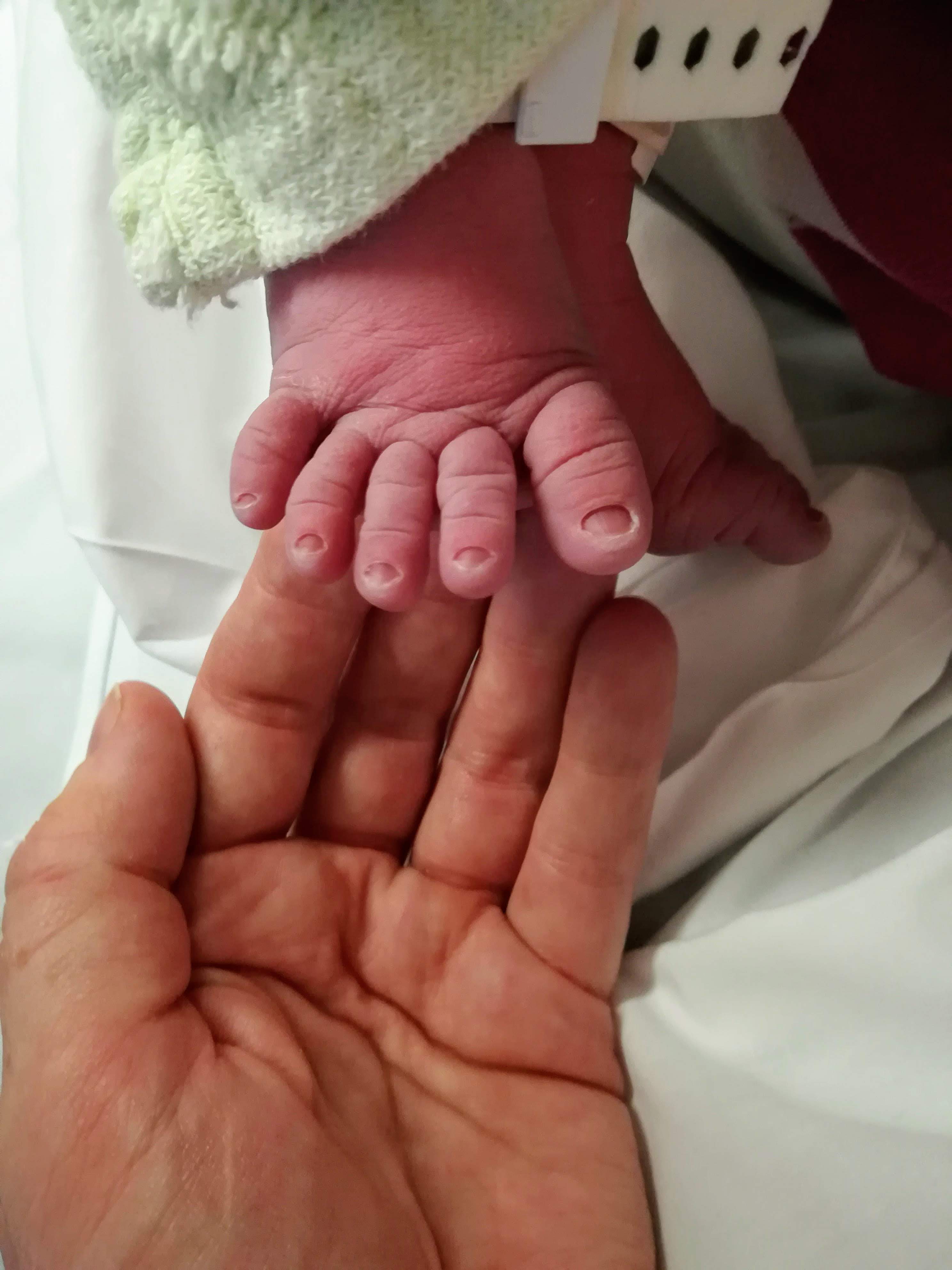 A new mum holding their newborns foot. Bump and beyond wellness helps women through pregnancy using hypnobirthing and wellness psychology.