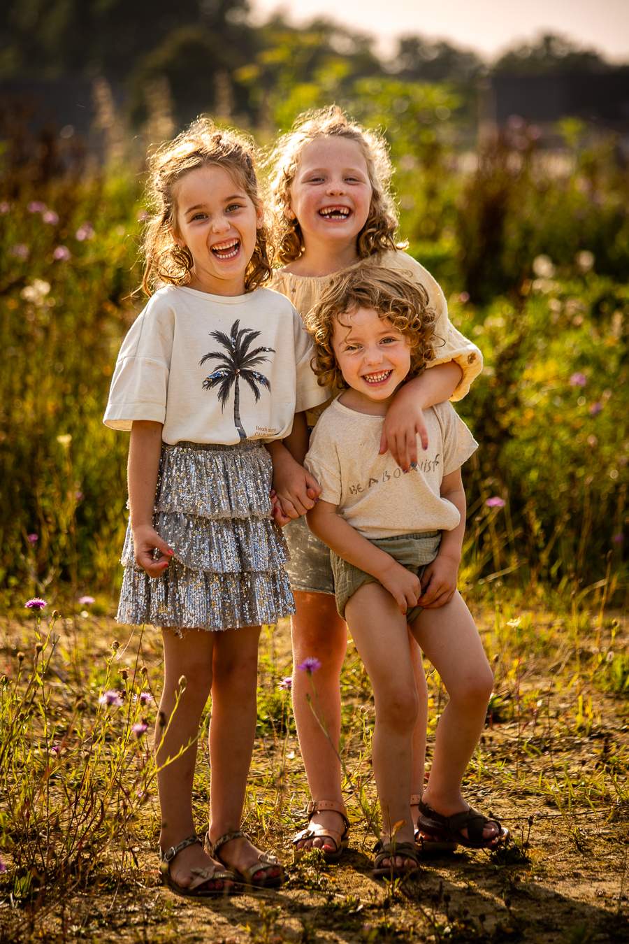 Twee zussen en een broertje lachend naar de fotograaf, stadsboerderij Turnhout.