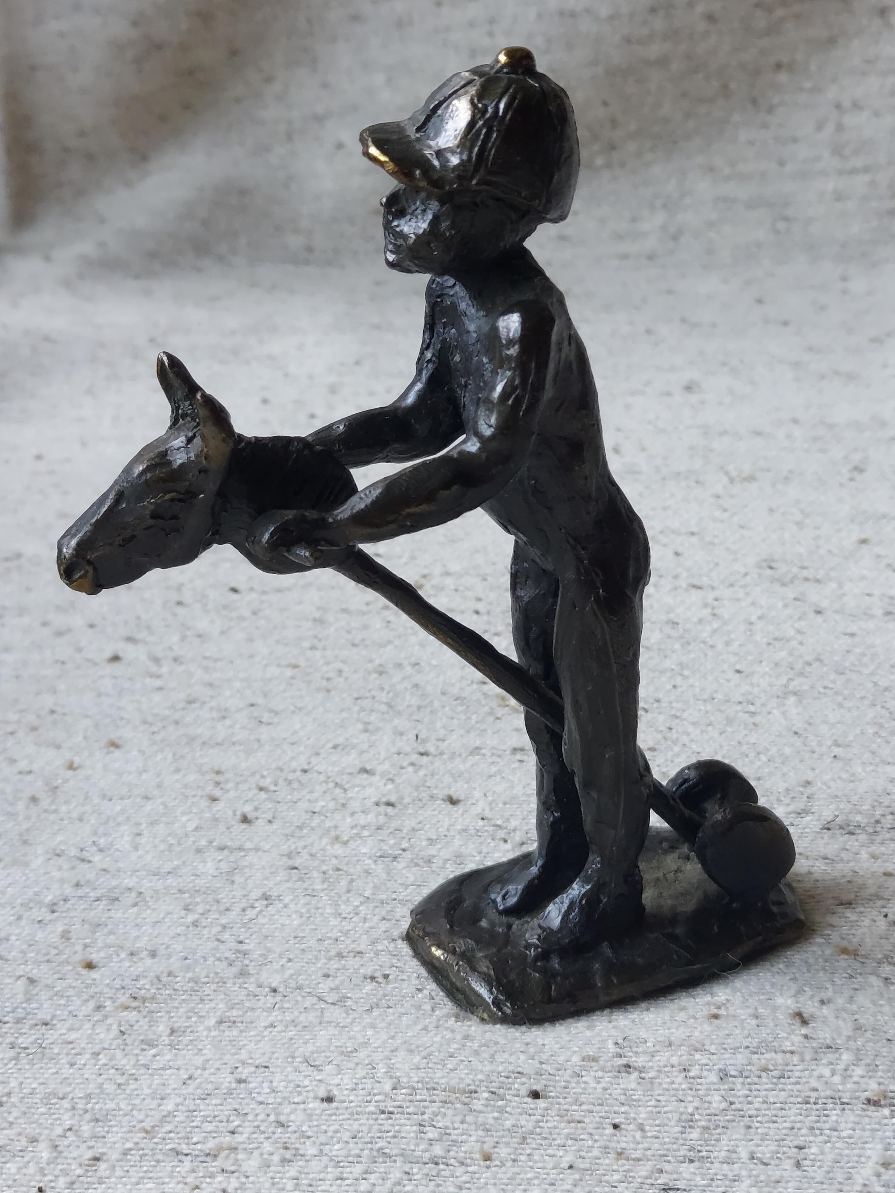 Bronzen beeld van kind op stokpaard