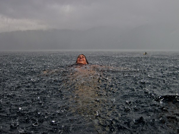 person in the water, in the rain, with a smile.