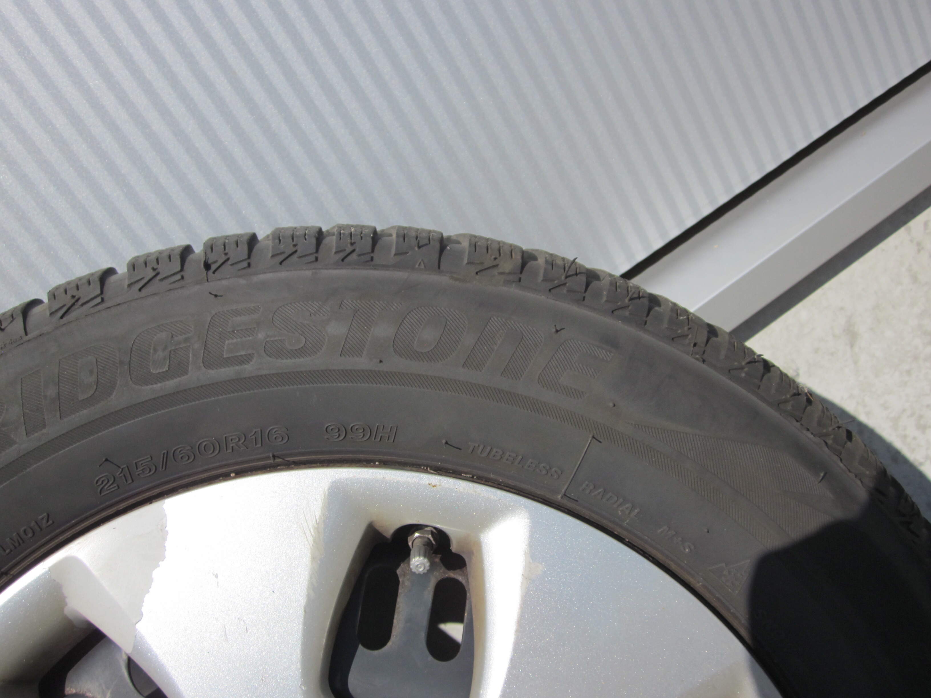 In nette staat Bridgestone winterbanden 215/60/R16 op stalen velg met opel wieldoppen