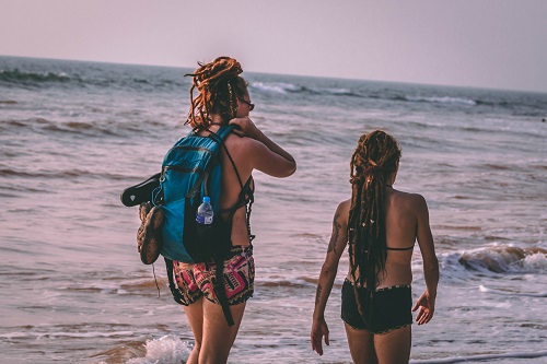 two women walking along a beach with a backpack, compact towels for backpacking