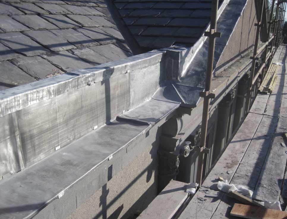 Newly slated roof with parapet stones covered with lead sheath to stop persistent dampness
