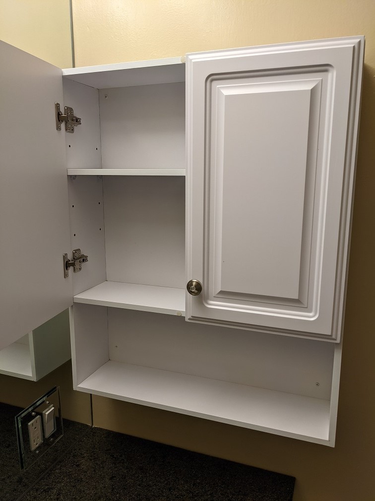 A brand-new white wall cabinet is installed in each bathroom