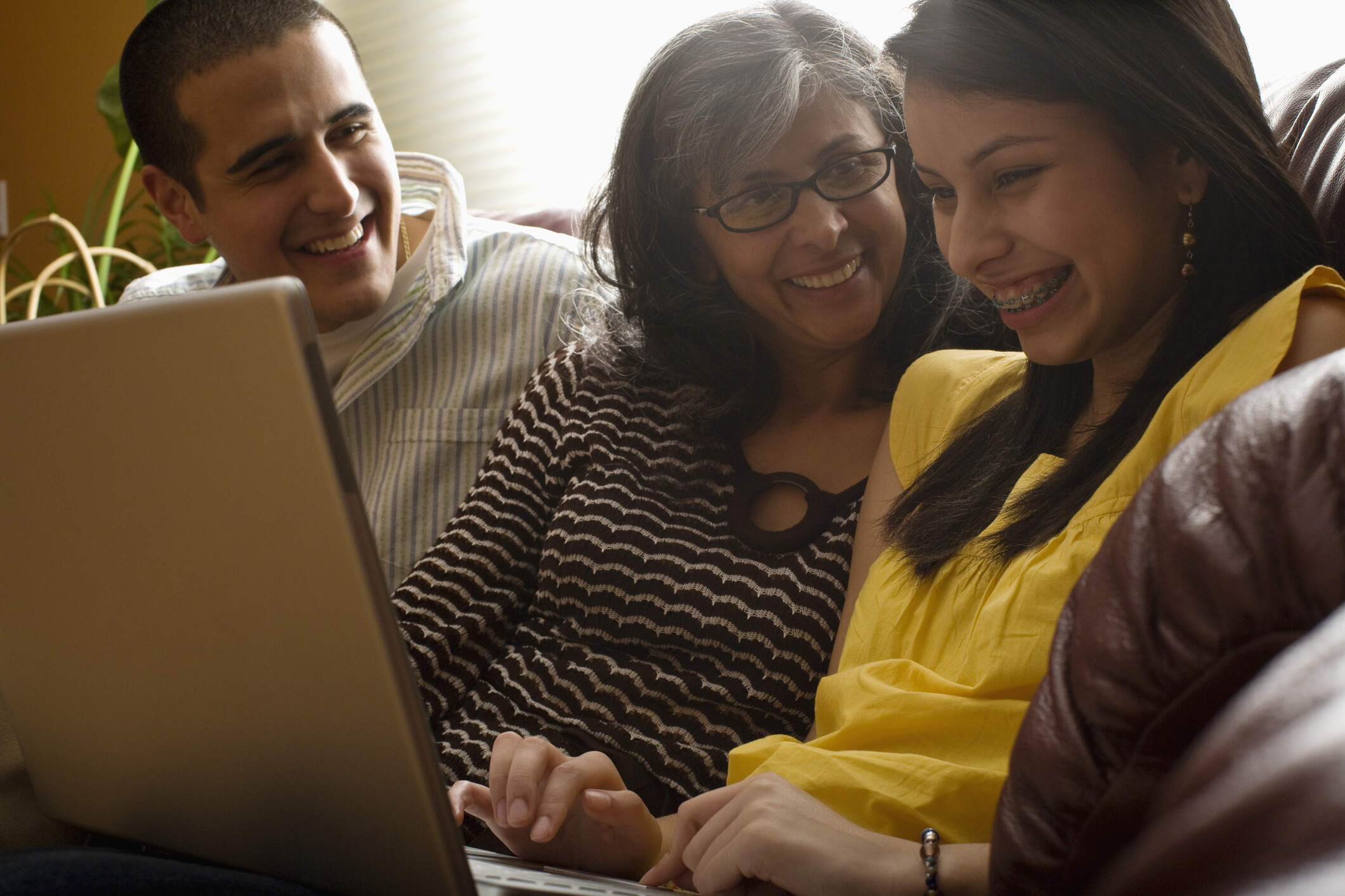 Parents in discussion with their teenager who is looking at their laptop